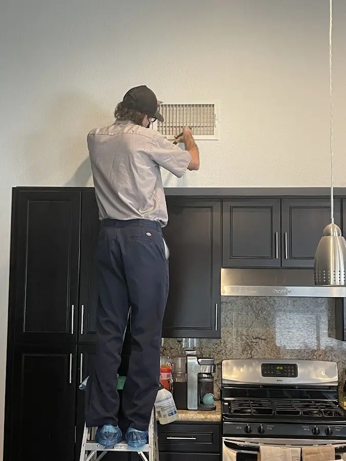 Technician inspecting an air vent during HVAC service in Lake City